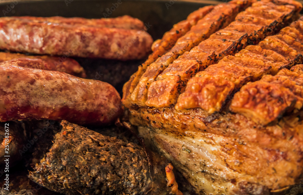 Roasted crispy pork ribs ,black pudding and sausages in oval metal baking dish. Roasted crispy pork ribs ,black pudding and sausages in oval metal baking dish.