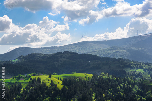 Beautiful summer mountain landscape in Apuseni mountains  Romania. Snow and wind turbines at the top of hills. Concept of green lifestyle  sustainability and energy. 