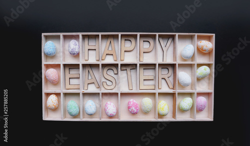 Easter eggs. Happy easter text. Holidays decoration black background. Decor elements in wooden containers