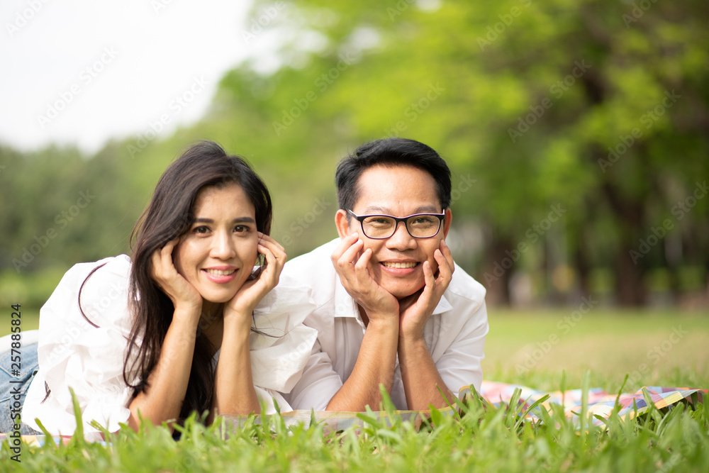 Portrait of happy young asian couple laying on grass In public park. Portrait of happy young asian couple laying on grass In public park.