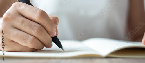 Businesswoman writing on notebook in office, hand of woman holding pen with signature on paper report. business concepts photo