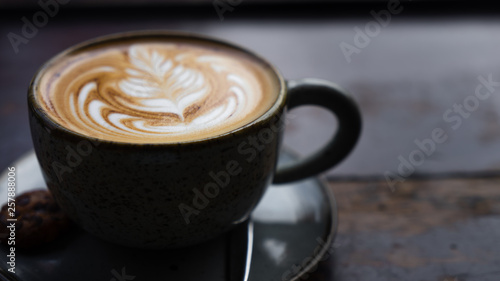 A perfectly crafted and delicious cappuccino coffee made with locally grown Indonesian coffee served on a worn wooden table with a latte art rosetta