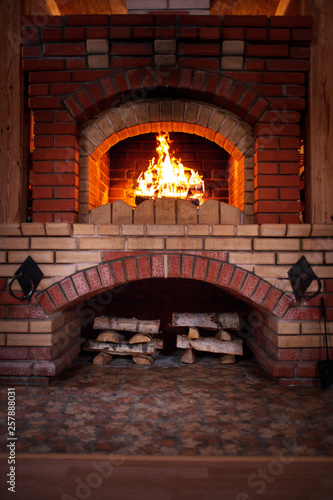bottom view of brick fireplace with burning firewood in rural house