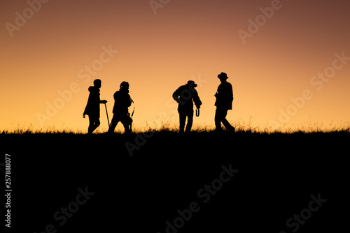 Silhouettes group of people on mountain with sunset