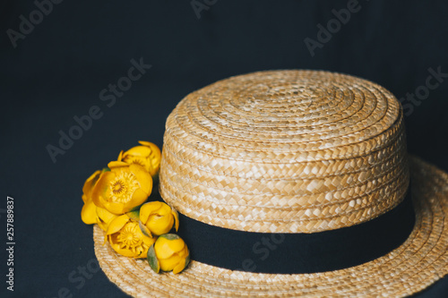 bouquet of yellow waterlily flower with green leaf. freshly ripped up. In a straw hat. close up on black background of fabric. yellow lotus. vanishing plant, red data book flower composition. Flat lay