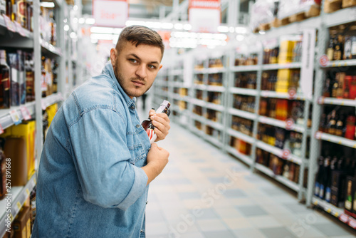 Fotografi Man hides bottle of alcohol under his shirt