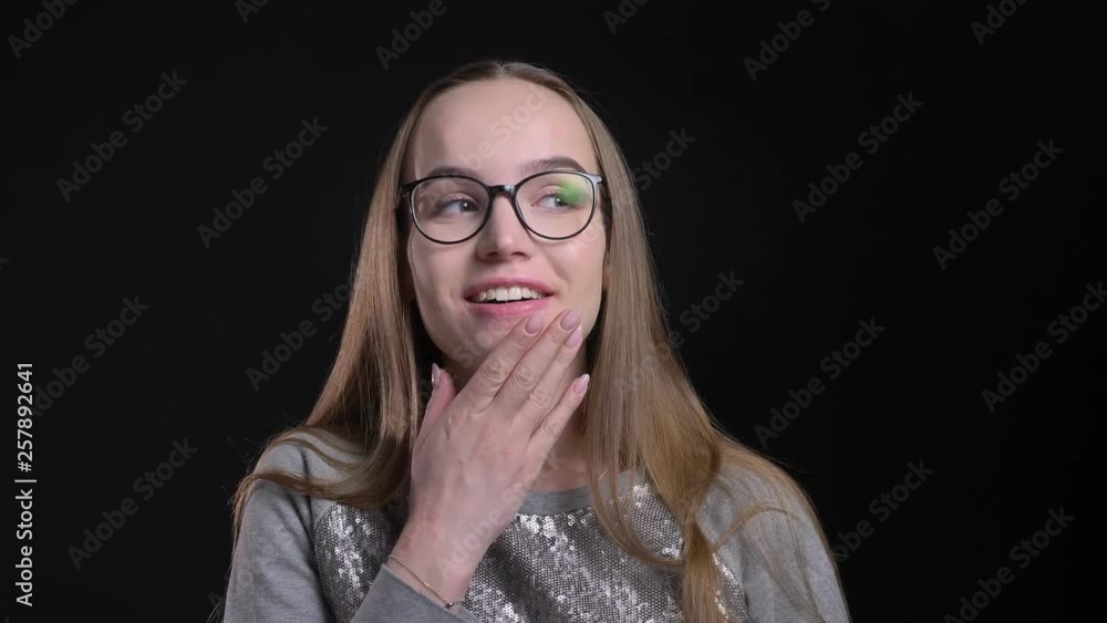Closeup shoot of young attractive hipster female in glasses getting surprised and smiling happily looking straight at camera with background isolated on black Closeup shoot of young attractive hipster female in glasses getting surprised and smiling happily looking straight at camera with background isolated on black