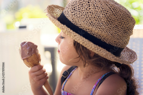 Little girl eating an ice cream cone at summer