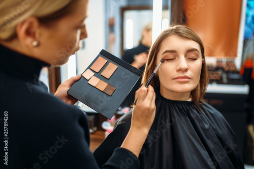 Visagiste and lady chooses cosmetic in makeup shop