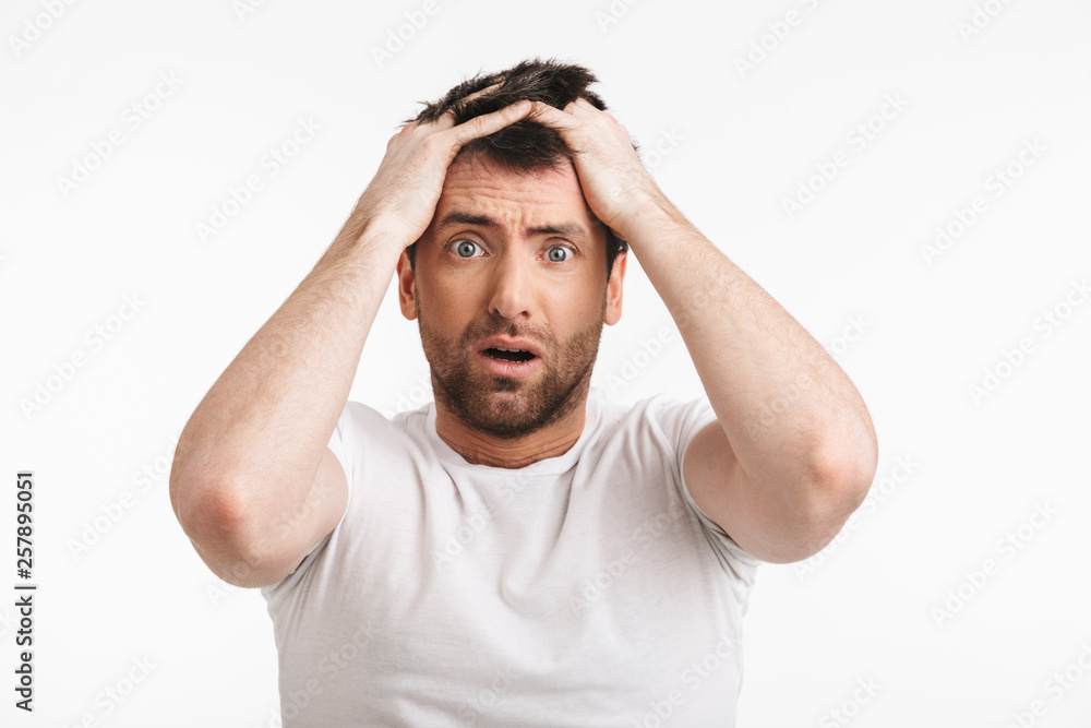 Naklejka premium Image of shocked man 30s with bristle in casual t-shirt frowning and grabbing head