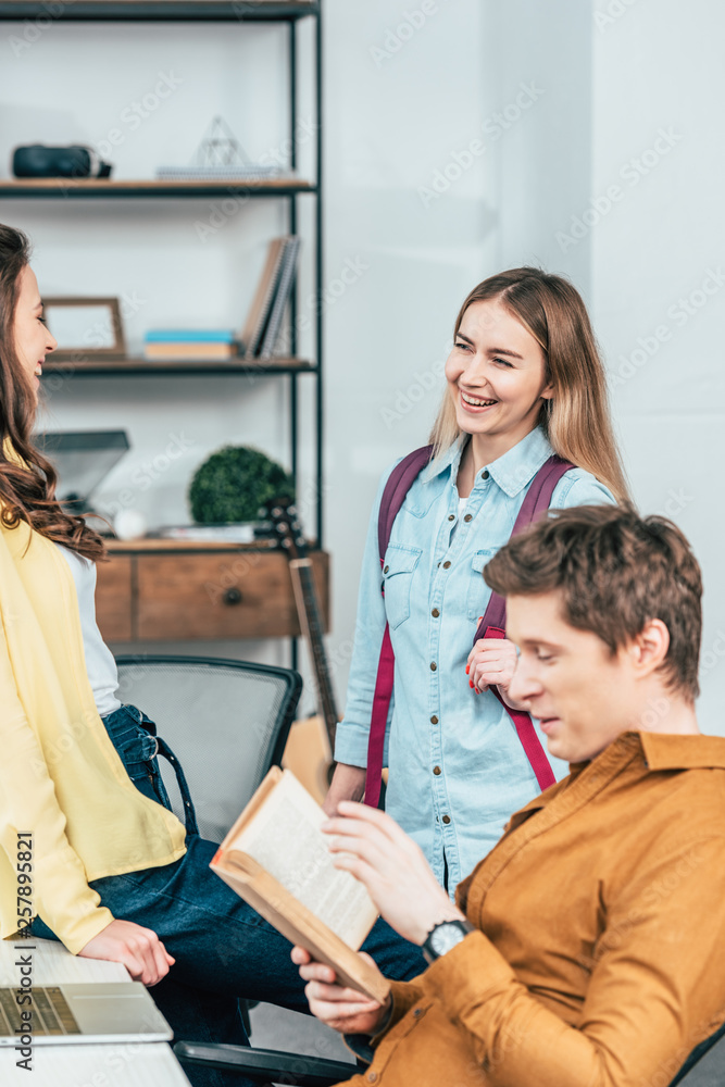 Obraz premium Three smiling students talking while studying together at table