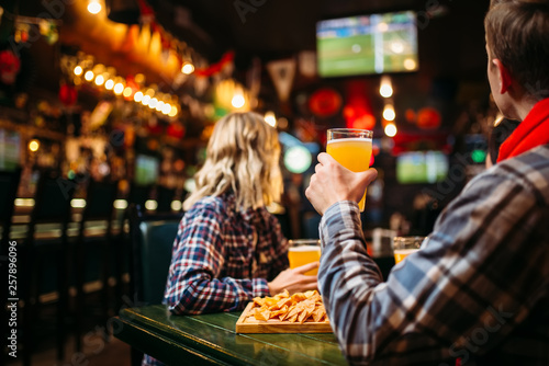 Fans watching match and drinks beer in sports bar