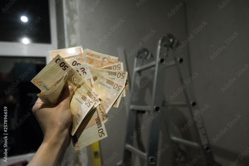 Construction worker receives the payment or salary. Expensive renovation at home or apartment. Concept of illegal money, shadow economy. Counting euro bills
