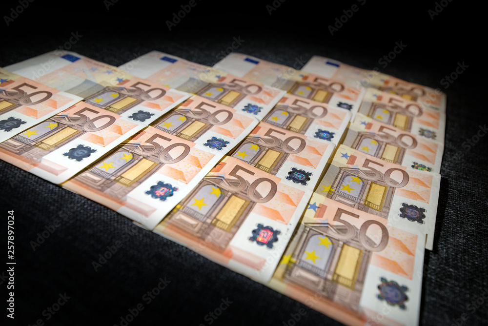 50 euro paper money on black background. Hundreds of banknotes. Concept of cash flow, finances, rich people, millionaire and successful business. 