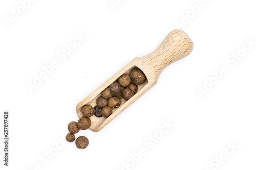 Lot of whole dry brown allspice berries with wooden scoop flatlay isolated on white background