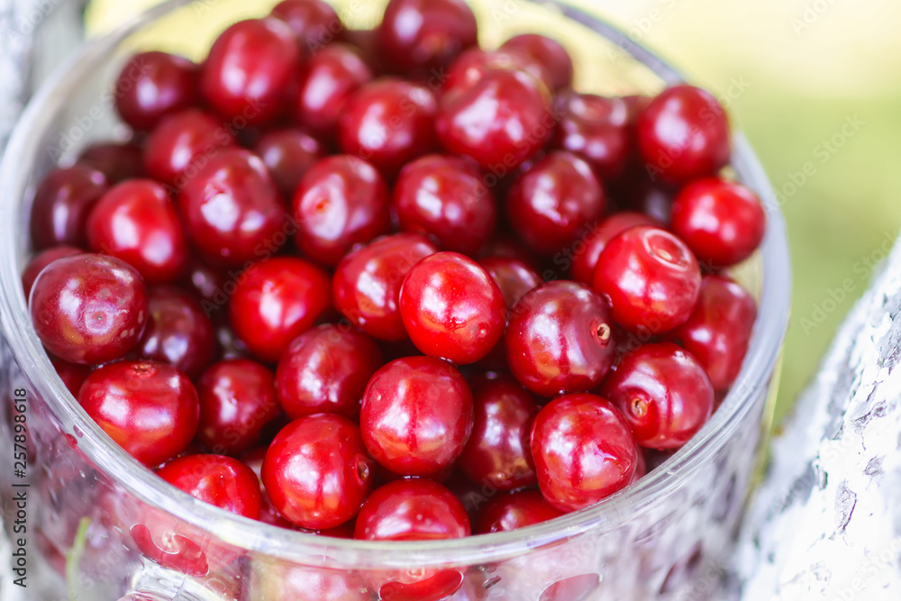 Ripe cherries in a transparent cup. Fresh red cherry fruits in summer garden in the countryside. Ripe cherries in a transparent cup. Fresh red cherry fruits in summer garden in the countryside.