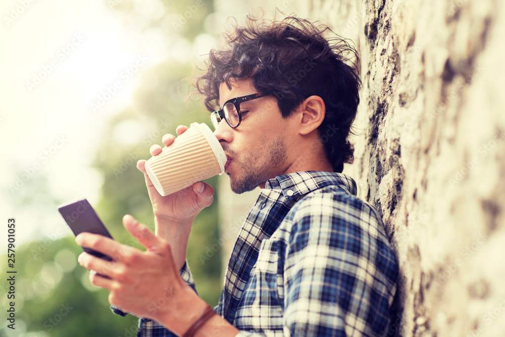 Fototapeta premium leisure, technology, communication and people concept - man with smartphone drinking coffee from disposable paper cup and texting message on city street