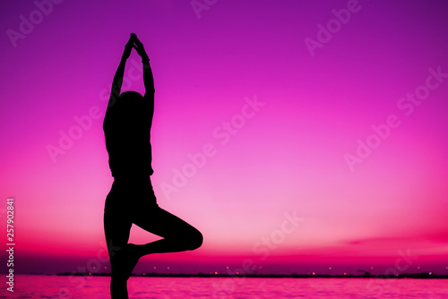 Silhouette meditating yoga pose woman practice  on the beach in sunset background ,lifestyle and healthy concept.