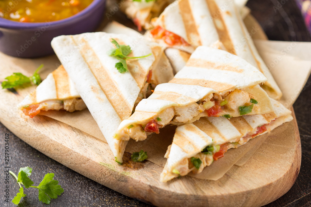 Mexican quesadilla with chicken, tomatoes, cheese and grilled sauce. Tasty snack in a pellet, healthy food