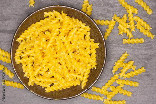 Lot of pieces of raw italitan yellow pasta torti in a grey ceramic bowl flatlay on grey stone photo