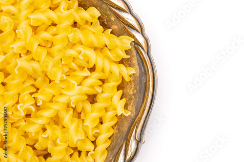 Lot of pieces of raw italitan yellow pasta torti in a grey ceramic bowl in old iron bowl flatlay isolated on white background photo