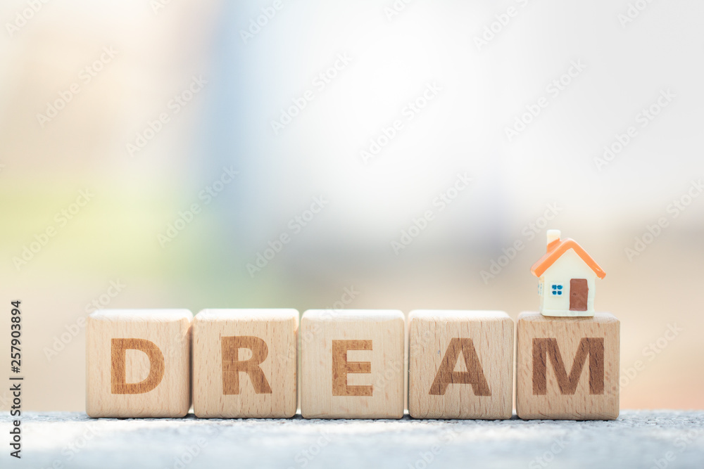 Miniature house model on wooden block text dream. Business, finance, and saving money for dream house concept Miniature house model on wooden block text dream. Business, finance, and saving money for dream house concept