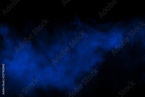 Blue color powder explosion cloud on black background.Closeup of Blue dust particles exhale on dark background.