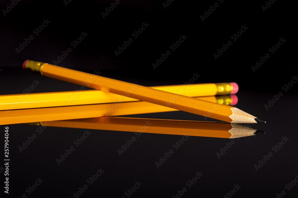 Group of two whole yellow pencil isolated on black glass Group of two whole yellow pencil isolated on black glass
