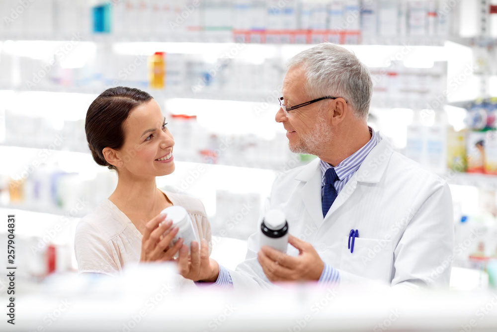 Obraz premium medicine, healthcare and people concept - senior apothecary with drugs and female customer at pharmacy