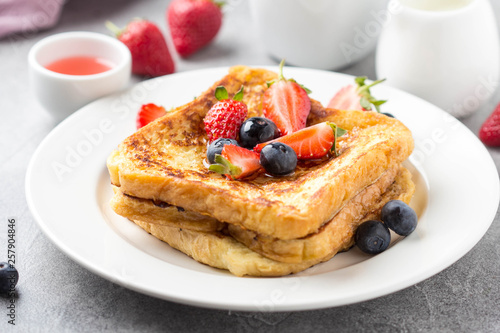 French toast with berries (blueberries, strawberries) and sauce, traditional sweet dessert of bread with egg and milk. Morning baking food