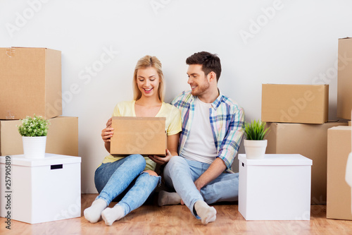 mortgage, people and real estate concept - happy couple with boxes moving to new home