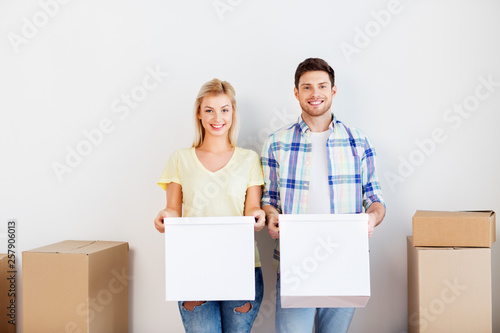 mortgage, moving, people and real estate concept - happy couple with cardboard boxes at new home