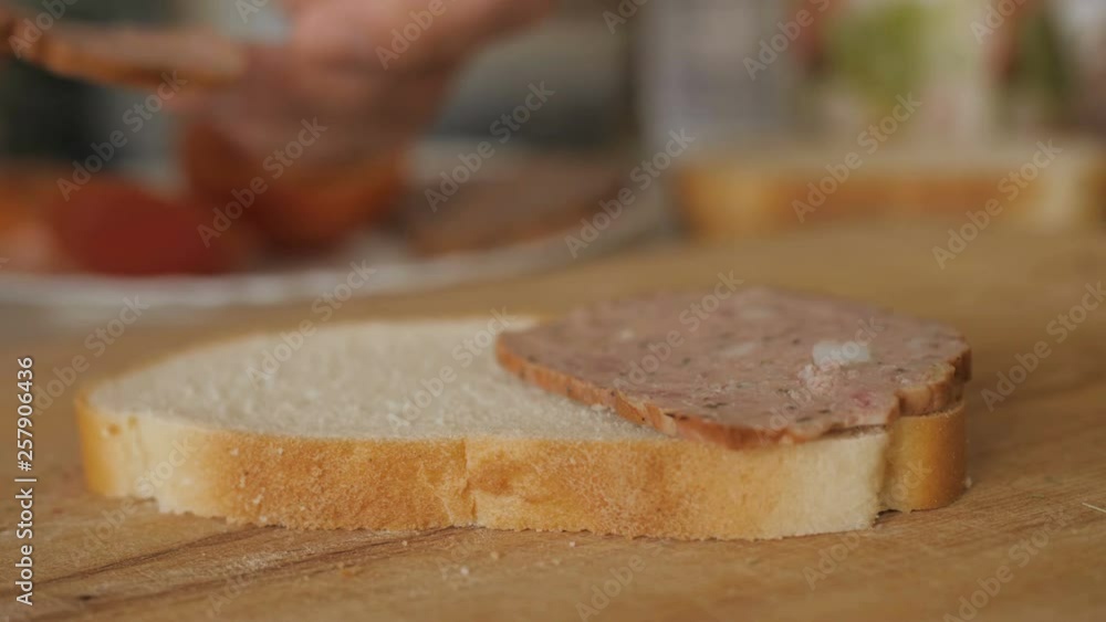 Detail of kitchen table with food and male hands making sausage sandwich, close up. Man cooking sandwich with sausage and tomato on a wooden table in the rustic kitchen Shooting closeup. Slow motion. Detail of kitchen table with food and male hands making sausage sandwich, close up. Man cooking sandwich with sausage and tomato on a wooden table in the rustic kitchen Shooting closeup. Slow motion.