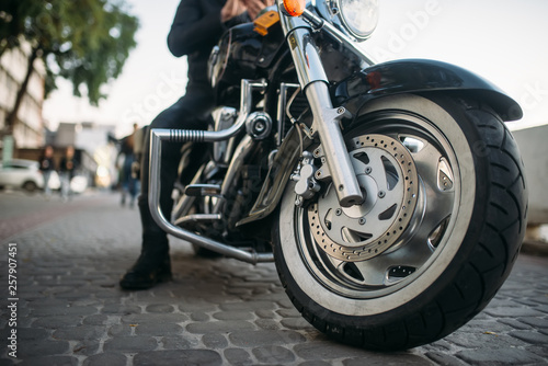Biker poses on motorcycle, front view from ground