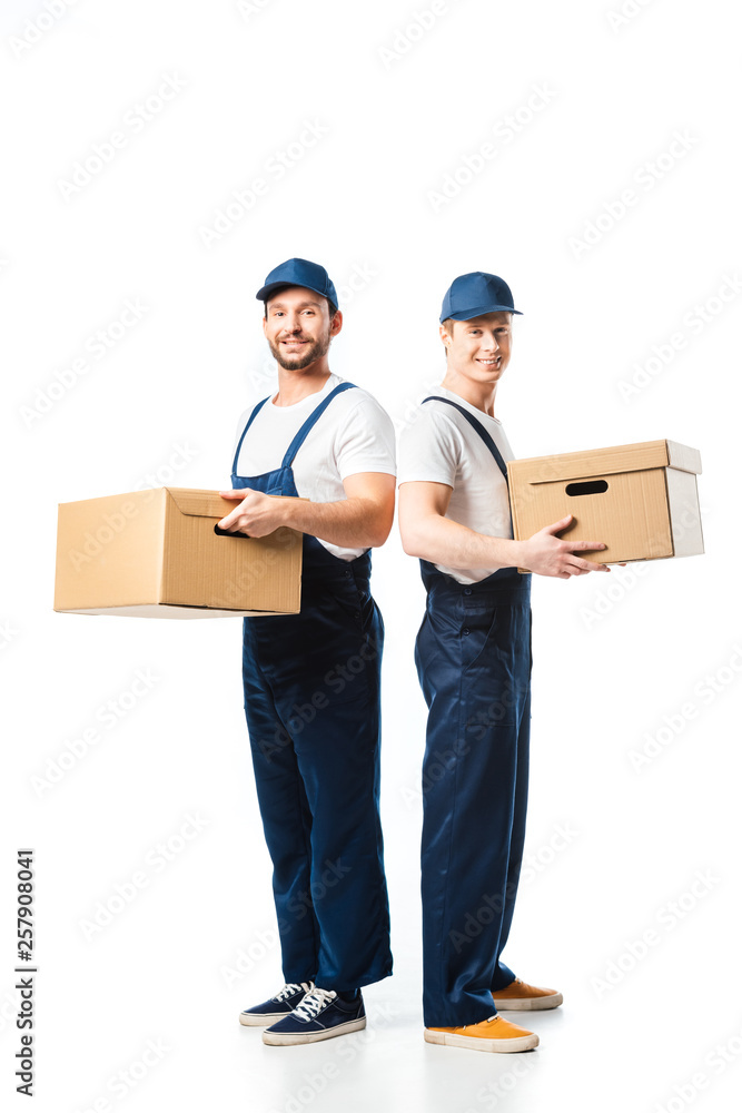 two handsome movers looking at camera while transporting cardboard boxes on white two handsome movers looking at camera while transporting cardboard boxes on white