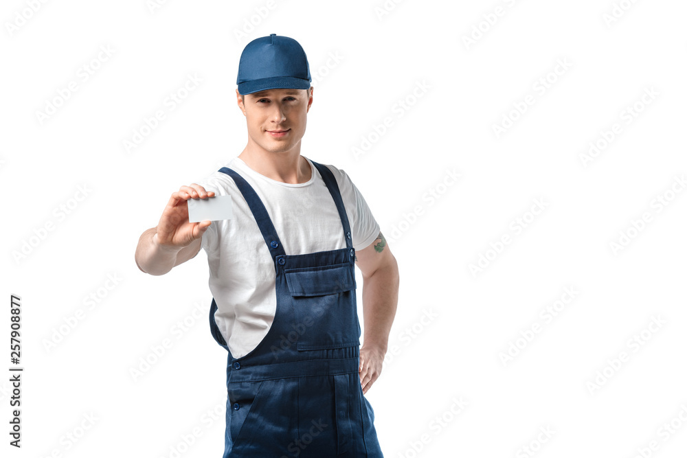 handsome mover in uniform looking at camera and holding blank business card isolated on white with copy space handsome mover in uniform looking at camera and holding blank business card isolated on white with copy space