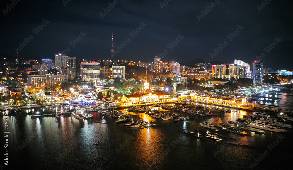 Sochi sea port. Aerial drone. Berth for marine yachts and boats. The historic building of the seaport. Evening illumination of the city.