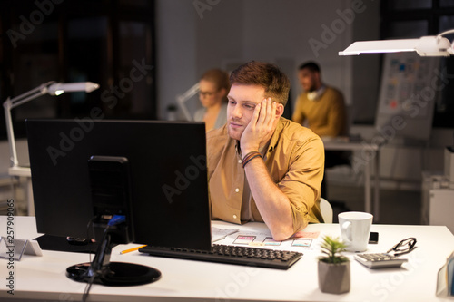 business, overwork, deadline and people concept - tired or bored man working at computer at night office