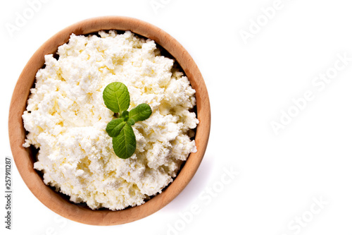 homemade cottage cheese in a wooden bowl, mint lie on a white background