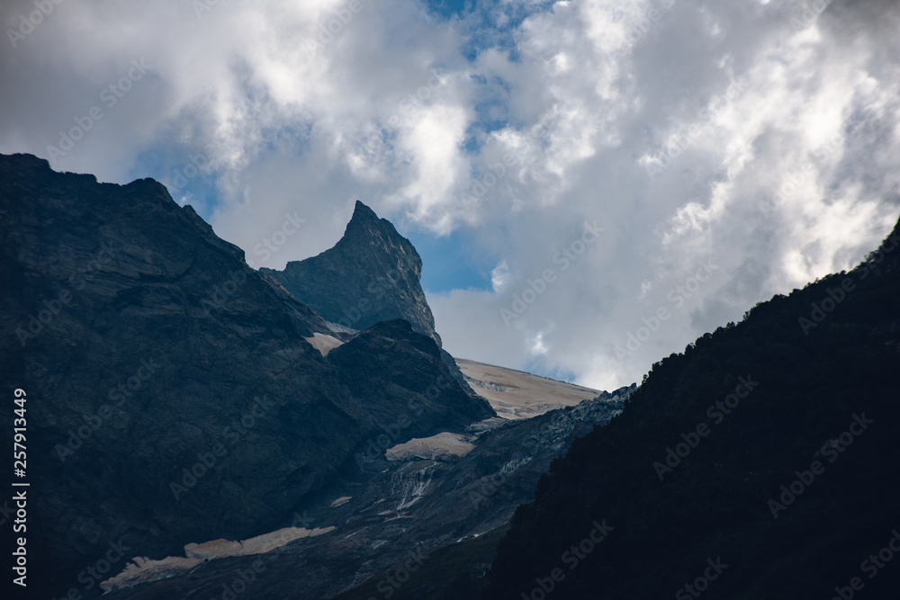 Massive peaks of the Caucasus Mountains in the snow in the surroundings of dombai in the clouds. Summer day. Massive peaks of the Caucasus Mountains in the snow in the surroundings of dombai in the clouds. Summer day.
