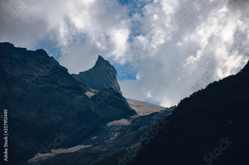 Massive peaks of the Caucasus Mountains in the snow in the surroundings of dombai in the clouds. Summer day.