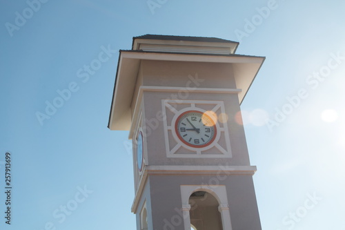 clock big tower with light flare and blue clear sky background .