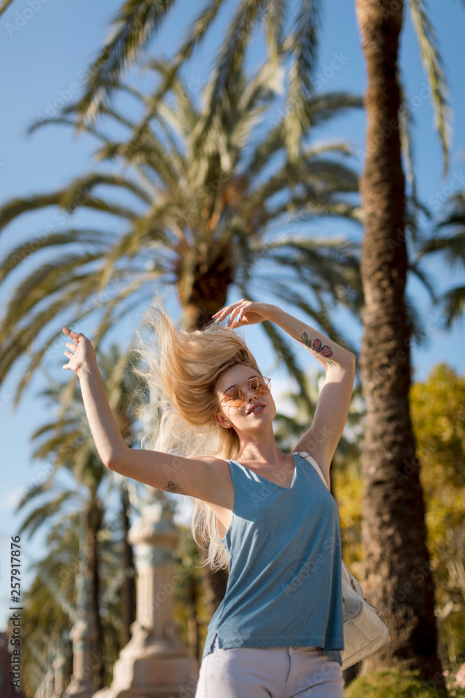 Carefree young woman moving under palm tree Carefree young woman moving under palm tree