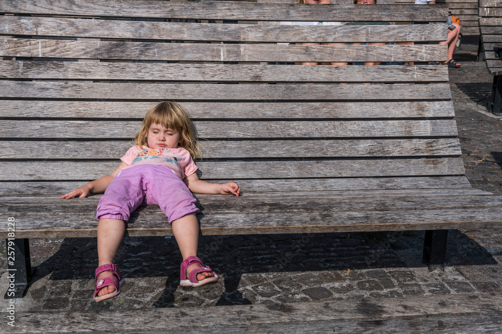 Sweden, girl lying on wooden bench on town square Sweden, girl lying on wooden bench on town square