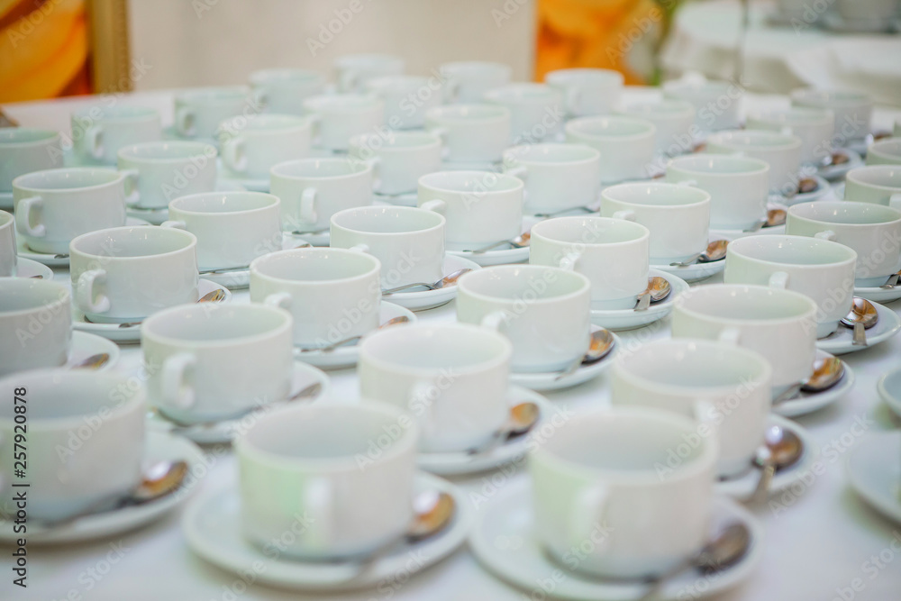 lot of tea cups and saucers on the table covered with a white tablecloth lot of tea cups and saucers on the table covered with a white tablecloth
