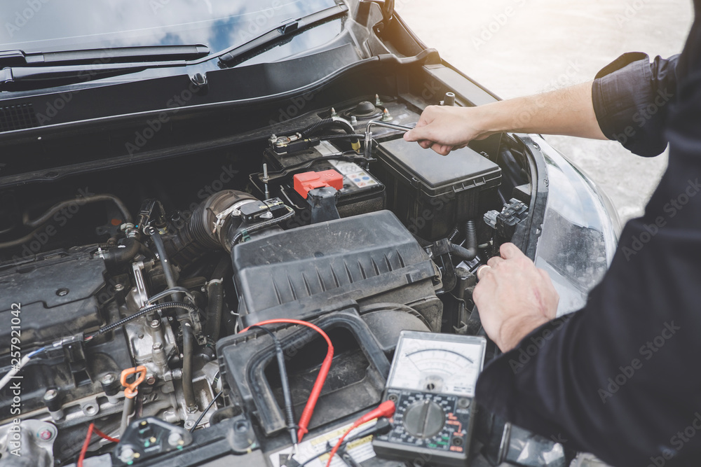 Services car engine machine concept, Automobile mechanic repairman hands repairing a car engine automotive workshop with a wrench and digital multimeter testing battery, car service and maintenance