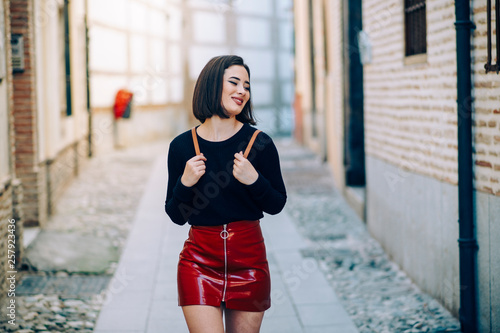 Portrait of young woman wearing red patent leather skirt with zipper photo