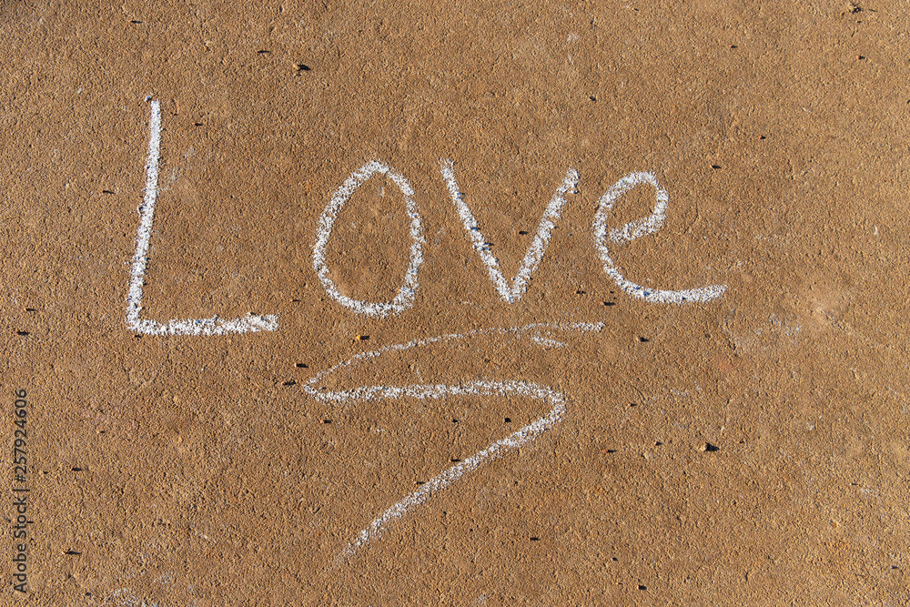 Fototapeta premium the word Love written with sidewalk chalk on gray concrete background