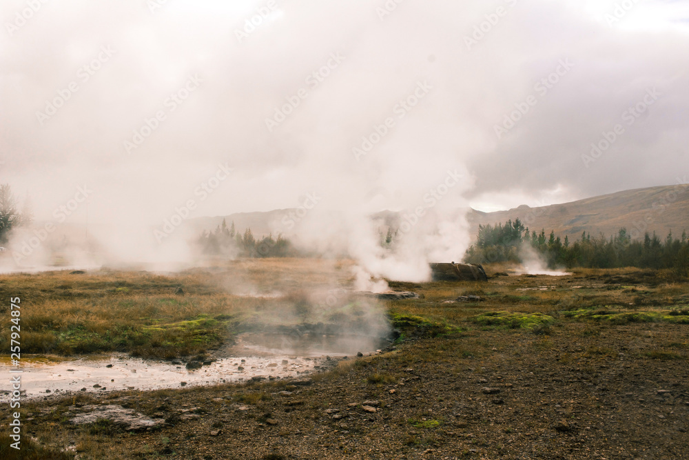 Fototapeta premium stunning Iceland geyser steam and mountains in plains