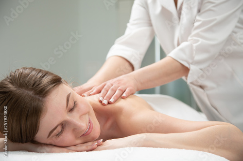 Relaxed woman receiving neck massage in wellness center